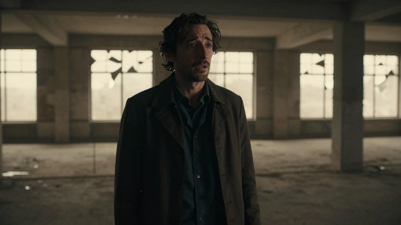 Adrien Brody standing alone in an architectural space, light filtering through broken windows.