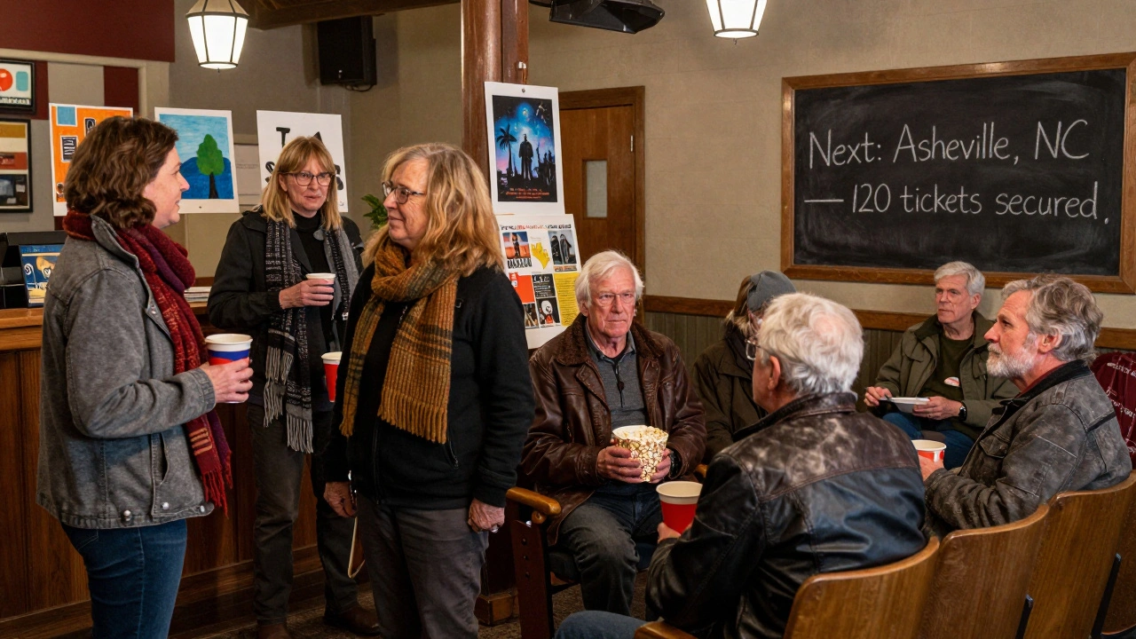 Community members chatting in a theater lobby after a screening, with handmade posters for sale.